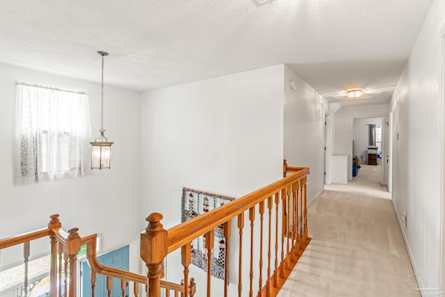 hallway with light carpet, an upstairs landing, and baseboards