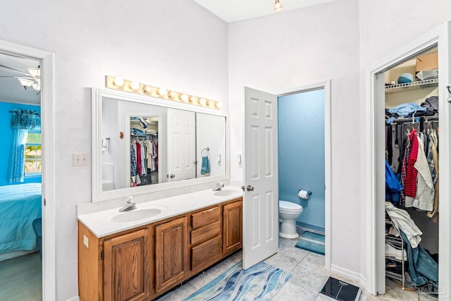 full bathroom featuring a sink, toilet, double vanity, and connected bathroom