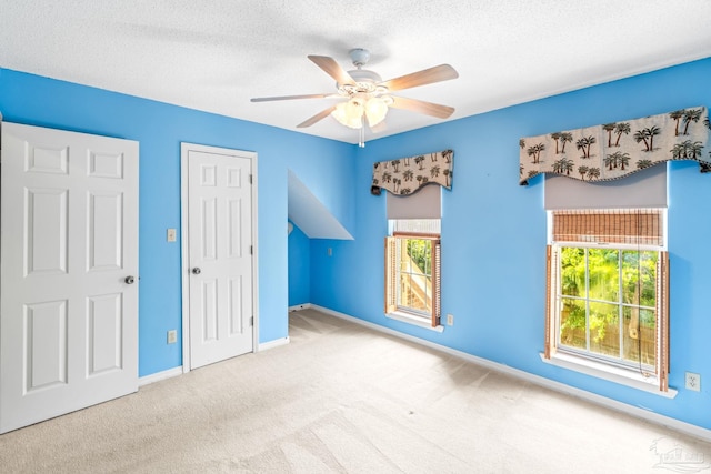 interior space featuring baseboards, a ceiling fan, carpet, and a textured ceiling