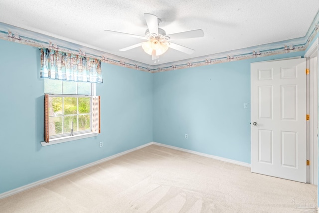 carpeted empty room featuring baseboards, a textured ceiling, and a ceiling fan