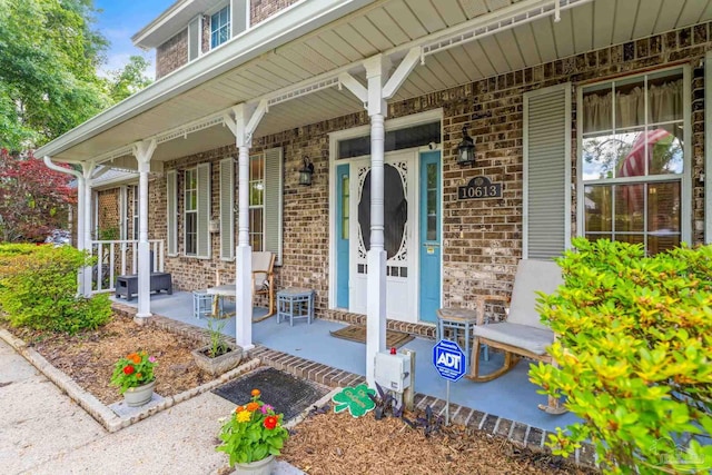doorway to property featuring brick siding and covered porch