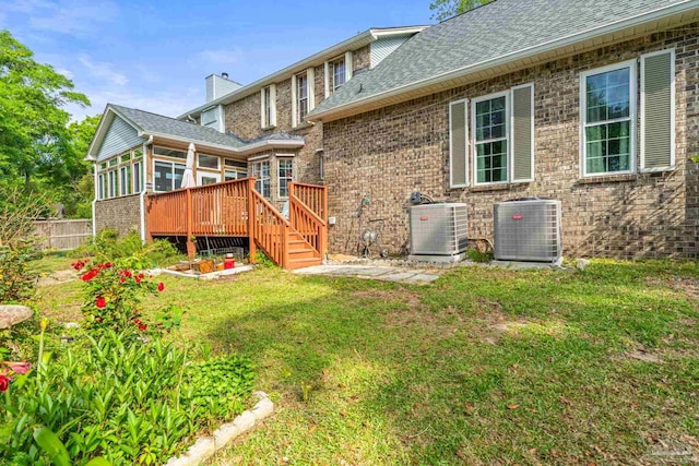 rear view of property with central AC, a chimney, a sunroom, and a lawn