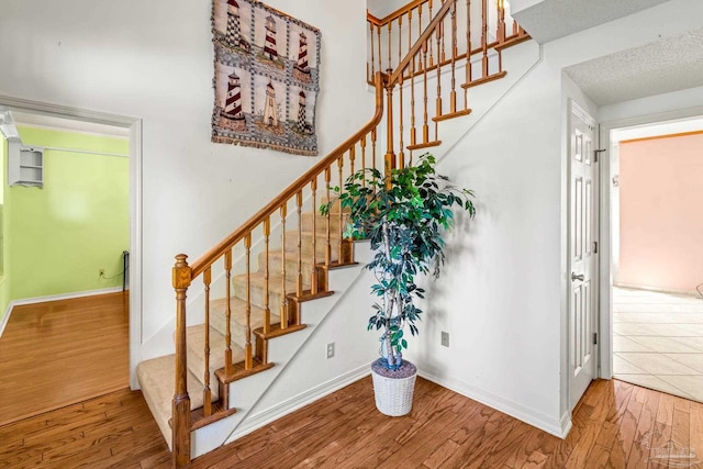 staircase with baseboards and wood finished floors