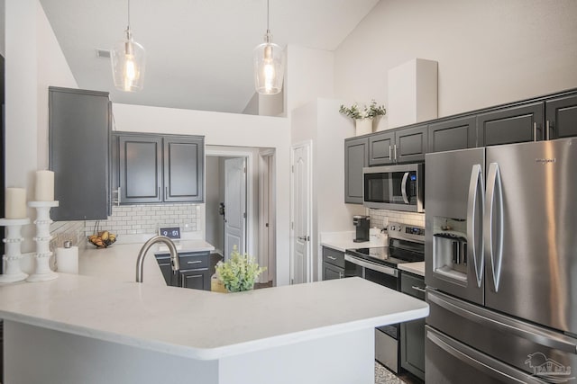 kitchen featuring a peninsula, vaulted ceiling, stainless steel appliances, and light countertops