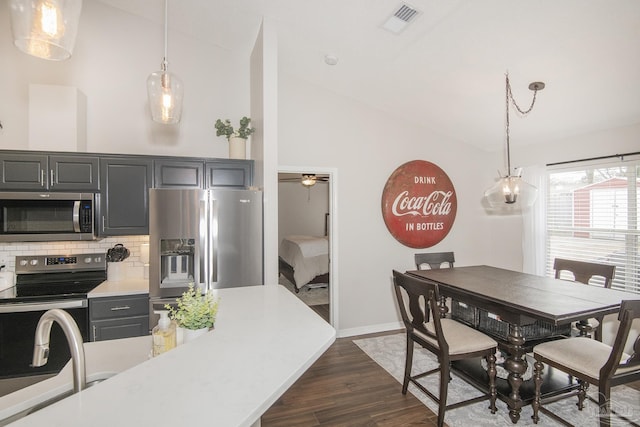 kitchen with dark wood-type flooring, decorative light fixtures, high vaulted ceiling, appliances with stainless steel finishes, and decorative backsplash