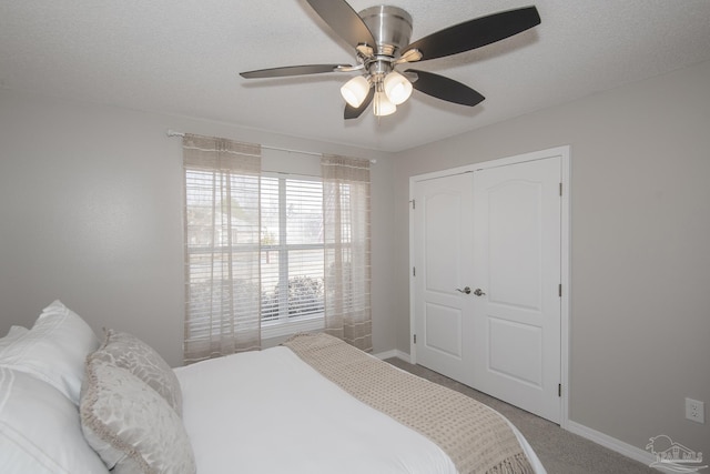 carpeted bedroom featuring a ceiling fan, a closet, a textured ceiling, and baseboards