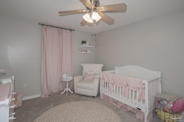 bedroom with carpet floors, a nursery area, ceiling fan, and a textured ceiling