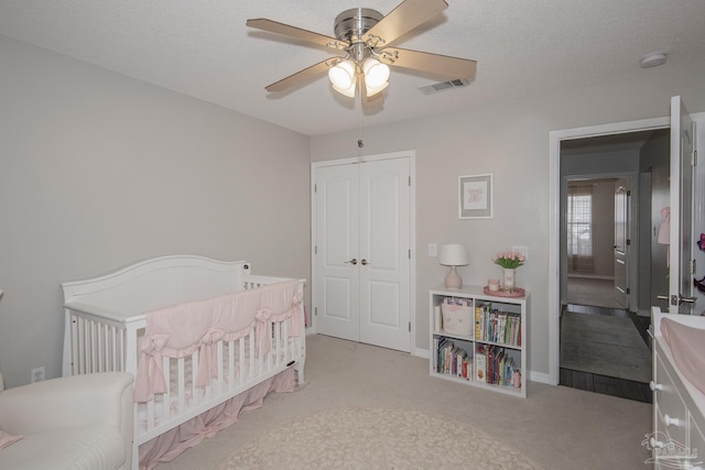 bedroom featuring carpet floors, a closet, visible vents, a textured ceiling, and a crib