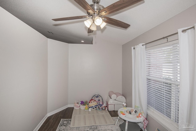 playroom with ceiling fan, baseboards, dark wood finished floors, and a textured ceiling