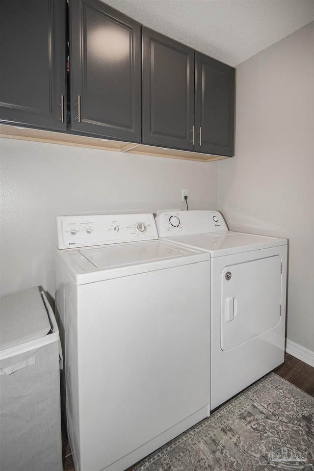 laundry area with cabinet space, washing machine and dryer, baseboards, and wood finished floors