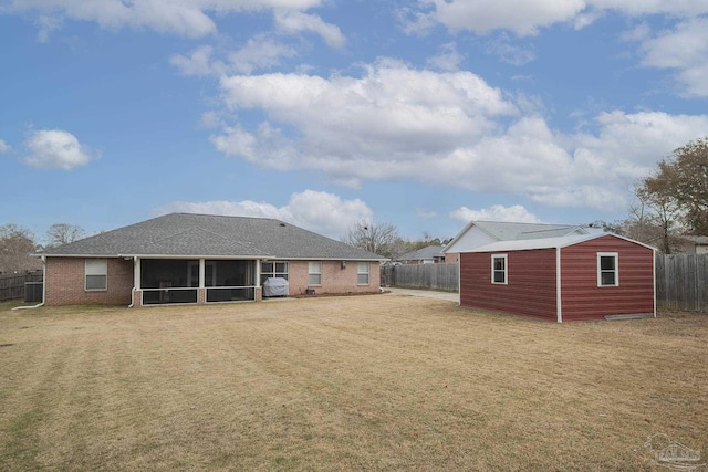 back of property featuring a sunroom, a yard, and an outdoor structure