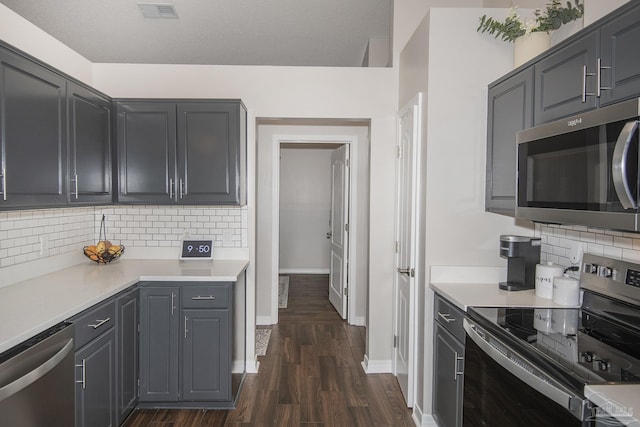 kitchen featuring visible vents, dark wood finished floors, stainless steel appliances, light countertops, and backsplash