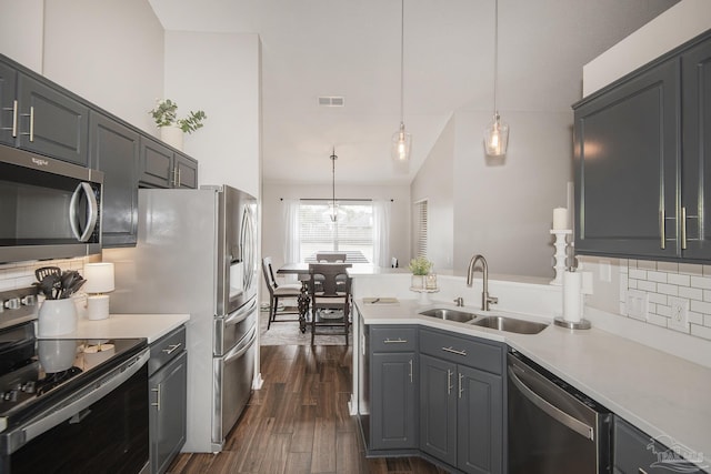 kitchen with appliances with stainless steel finishes, light countertops, a sink, and a peninsula