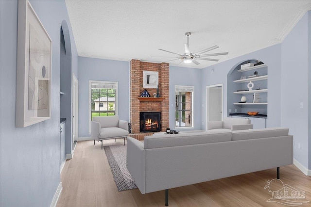 2574 1st Ct, Navarre, FL 32566 - living area with baseboards, built in shelves, a brick fireplace, light wood-style flooring, and ceiling fan
