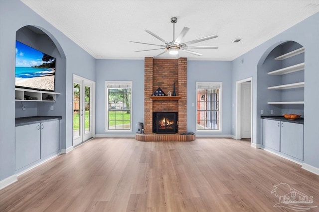 2574 1st Ct, Navarre, FL 32566 - unfurnished living room with a ceiling fan, light wood finished floors, a fireplace, built in features, and a textured ceiling