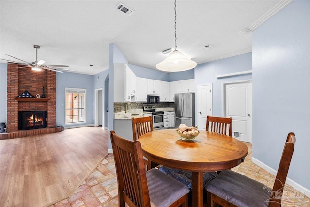 2574 1st Ct, Navarre, FL 32566 - dining space with ceiling fan, baseboards, and a brick fireplace