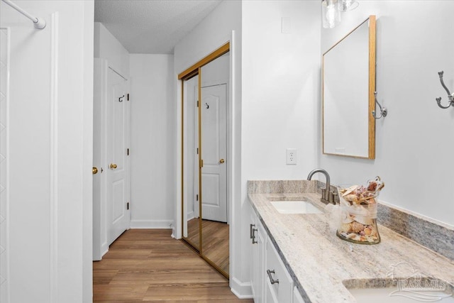 2574 1st Ct, Navarre, FL 32566 - bathroom with double vanity, wood finished floors, a closet, a textured ceiling, and baseboards