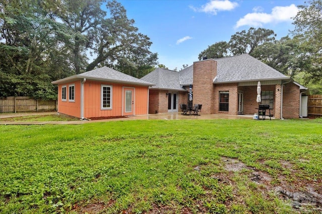 2574 1st Ct, Navarre, FL 32566 - back of property with a chimney, brick siding, a patio area, and a shingled roof