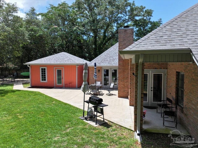 2574 1st Ct, Navarre, FL 32566 - back of property featuring a chimney, roof with shingles, a lawn, brick siding, and a patio