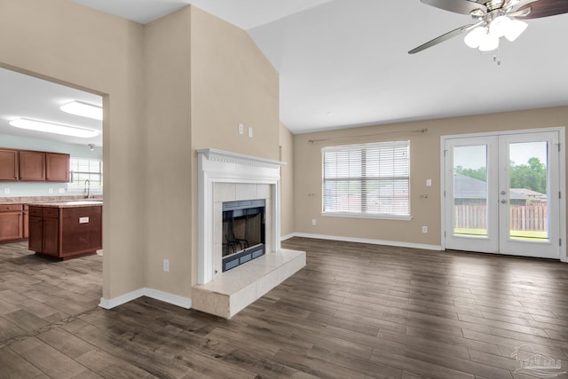 unfurnished living room featuring ceiling fan, hardwood / wood-style floors, a fireplace, sink, and high vaulted ceiling