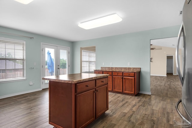 kitchen with a kitchen island, stainless steel refrigerator, and wood-type flooring