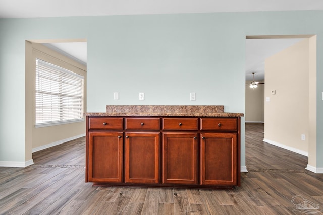 kitchen featuring wood-type flooring, ceiling fan, and light stone countertops