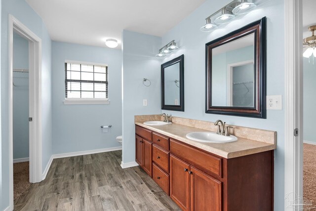 bathroom with double vanity, toilet, and hardwood / wood-style floors