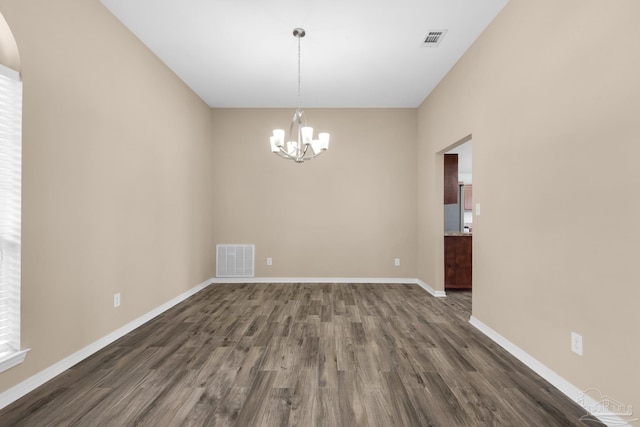 spare room featuring a notable chandelier and hardwood / wood-style floors