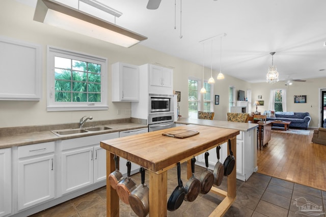 kitchen with pendant lighting, sink, dark wood-type flooring, white cabinetry, and appliances with stainless steel finishes