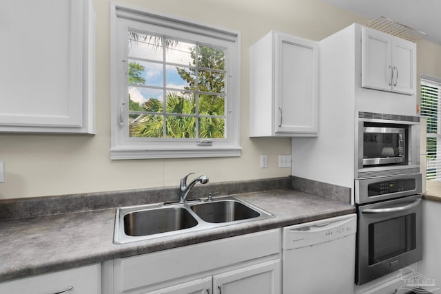 kitchen with appliances with stainless steel finishes, sink, and white cabinetry