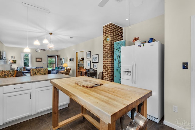 kitchen featuring hanging light fixtures, white cabinetry, white refrigerator with ice dispenser, dark tile patterned flooring, and ceiling fan