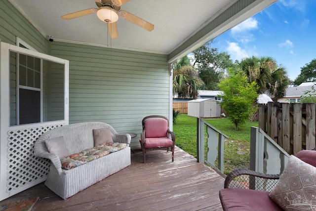 wooden terrace with a lawn, a storage shed, and ceiling fan