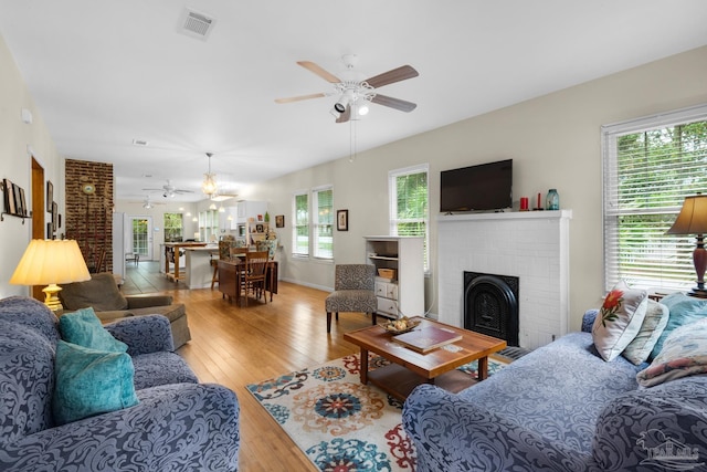 living room with light hardwood / wood-style floors, a fireplace, ceiling fan, and plenty of natural light