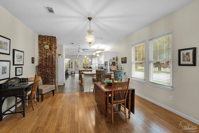 dining space featuring ceiling fan with notable chandelier, light hardwood / wood-style flooring, and a healthy amount of sunlight