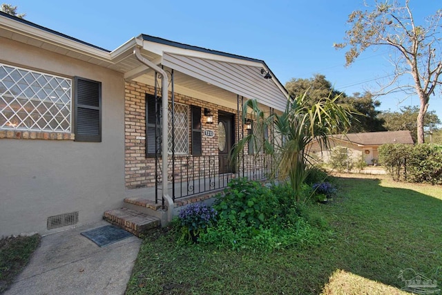 entrance to property with a lawn and a porch