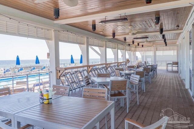 deck featuring outdoor dining area, a water view, and ceiling fan