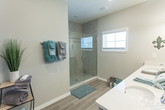 bathroom featuring a shower stall, baseboards, wood finish floors, and a sink