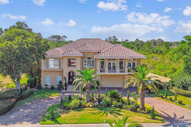 mediterranean / spanish house featuring aphalt driveway, french doors, a tile roof, stucco siding, and a balcony