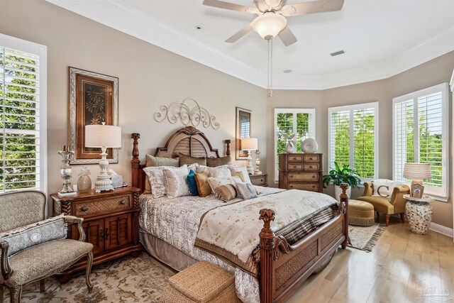 bedroom with light wood finished floors, visible vents, baseboards, a ceiling fan, and crown molding