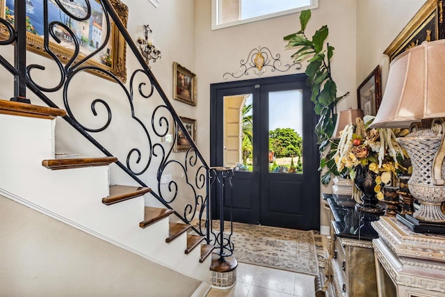 tiled entryway featuring french doors and a towering ceiling