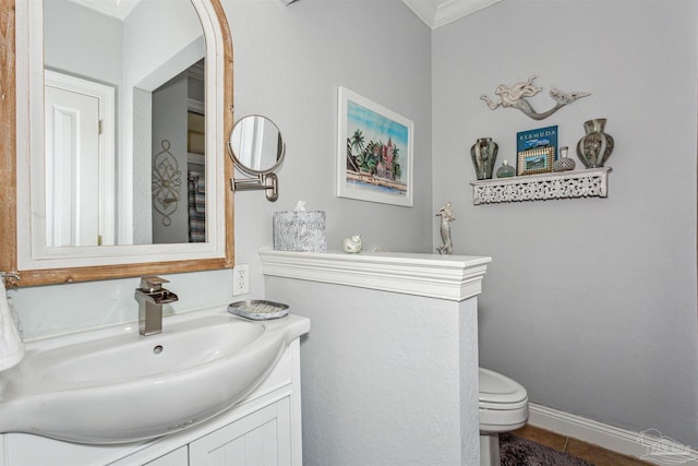 bathroom with toilet, vanity, baseboards, ornamental molding, and tile patterned floors