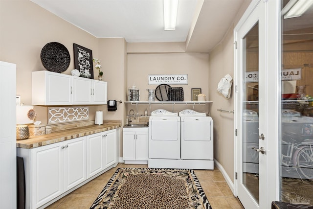 clothes washing area with light tile patterned flooring, sink, separate washer and dryer, and cabinets