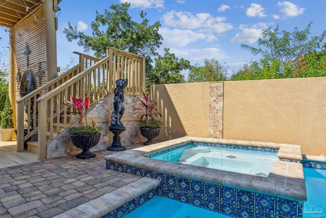 view of pool with stairs, an in ground hot tub, and fence