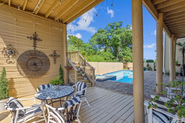 exterior space featuring a pool with connected hot tub, a patio area, a fenced backyard, a wooden deck, and stairs