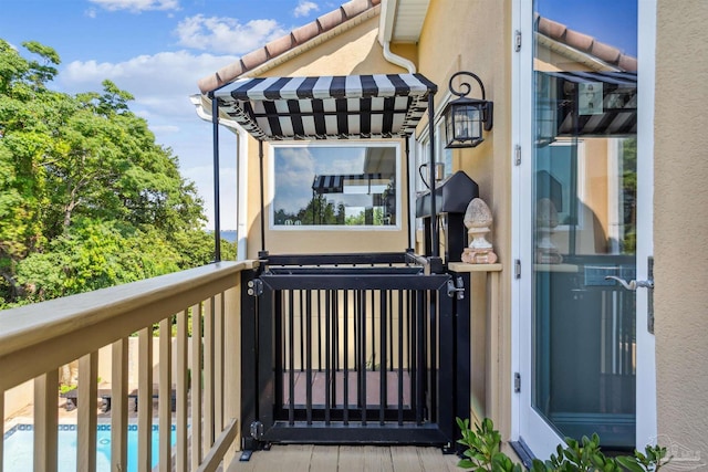 property entrance with a tile roof, a balcony, and stucco siding