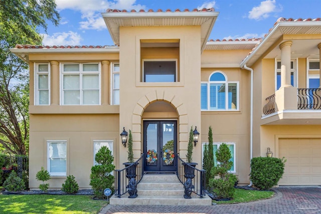 view of front of property featuring a balcony, a garage, and french doors