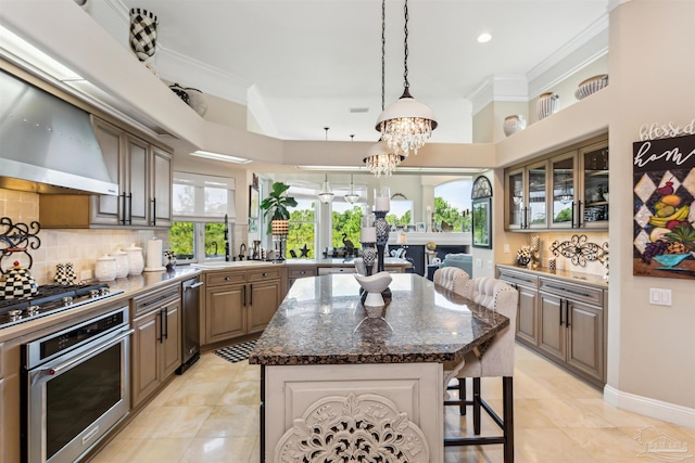 kitchen with appliances with stainless steel finishes, backsplash, a kitchen island, dark stone countertops, and a notable chandelier