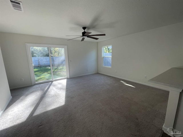 unfurnished living room featuring carpet floors, a wealth of natural light, ceiling fan, and a textured ceiling