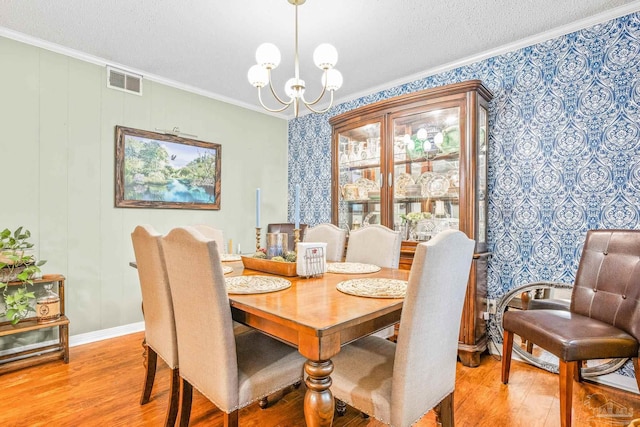 2803 Venetian Way, Gulf Breeze, FL 32563 - dining area with ornamental molding, light wood-type flooring, a chandelier, wallpapered walls, and a textured ceiling
