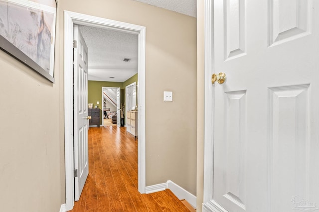 2803 Venetian Way, Gulf Breeze, FL 32563 - hall featuring a textured ceiling, wood finished floors, and baseboards